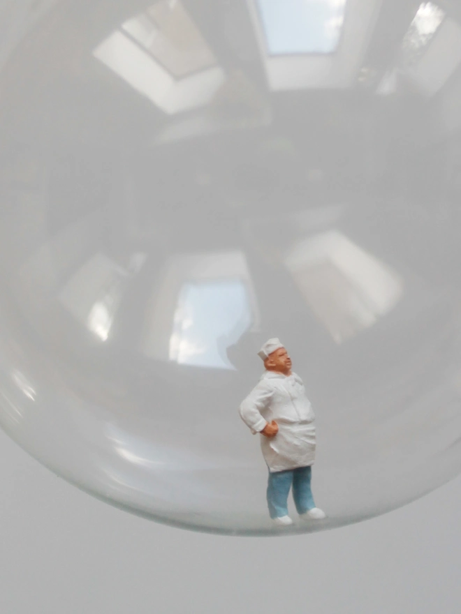 Miniature figure of a chef in a glass Christmas bauble - close up 