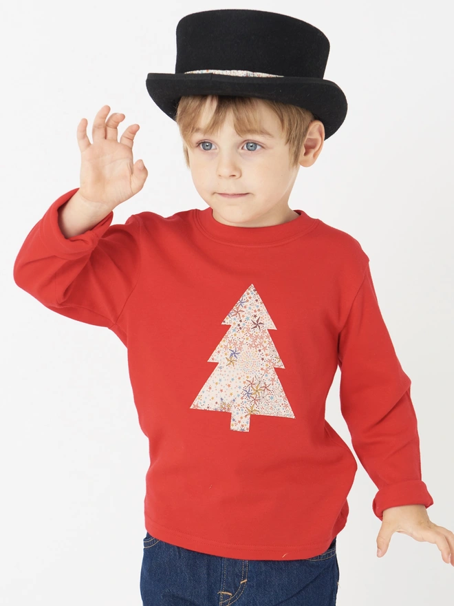 a 4 year old boy wearing a top hat and a red tee with a christmas tree cut from starry liberty print sewn onto the front