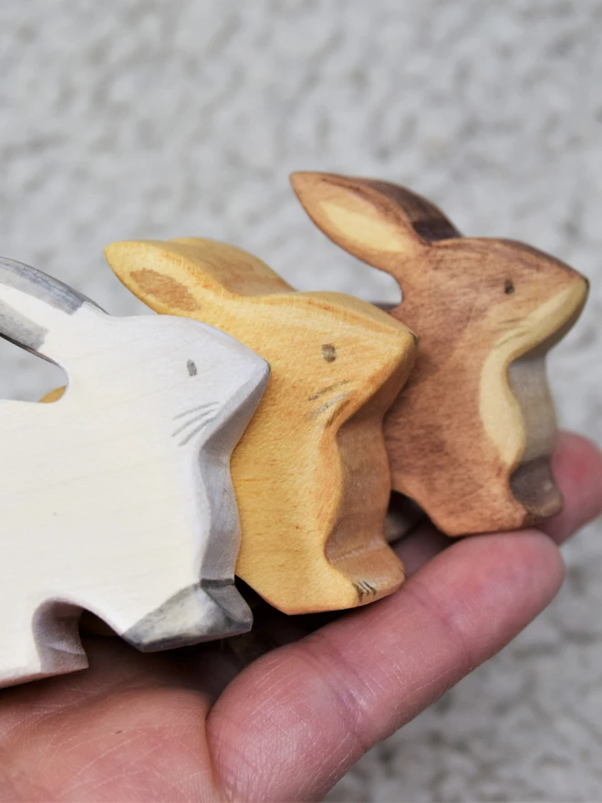 3 wooden rabbit toys made by eric and albert sitting in a hand