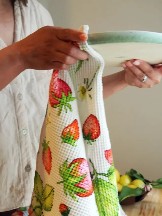 Strawberry Waffle Tea towel, being used to dry a plate. 