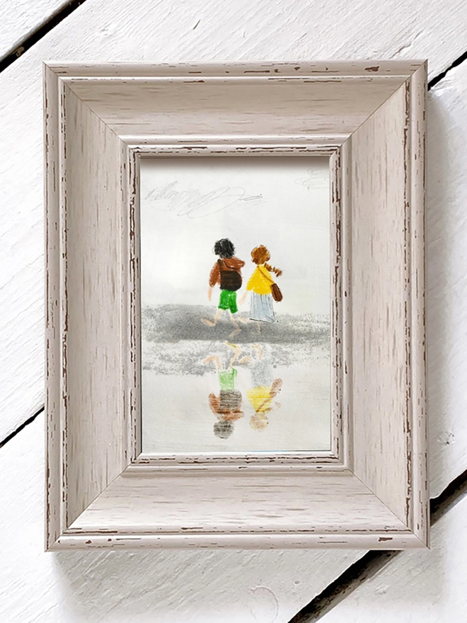 framed drawing of couple walking and reflected in the sand 