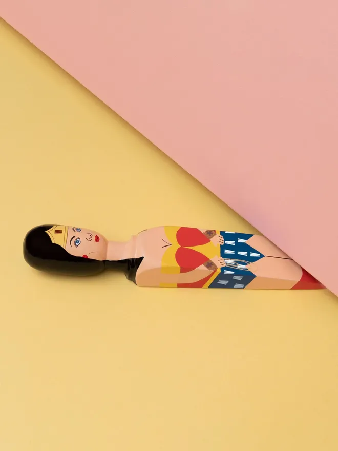 Wooden Door Stopper (Wonder Wedgie), a colourful wooden door stop sitting under a door.