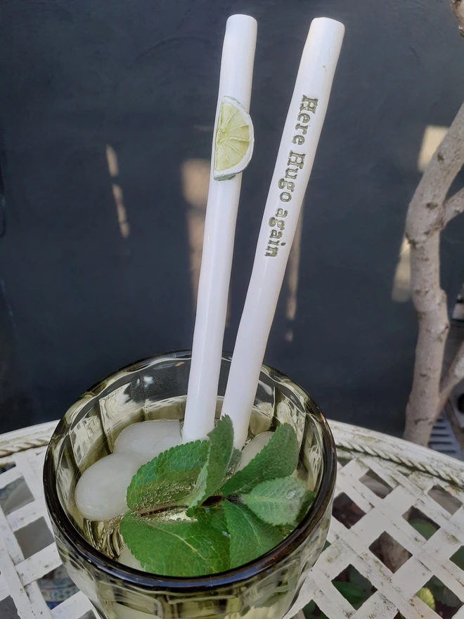 Reusable ceramic cocktail straws in a Hugo Spritz drink, featuring a lime slice motif and “Here Hugo again” text, styled in a glass with ice and mint leaves.