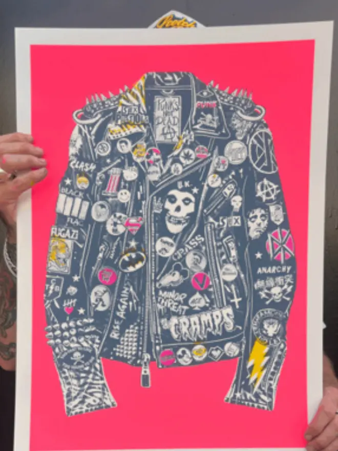 A punk leather jacket decorated with music band patches against a neon pink background.