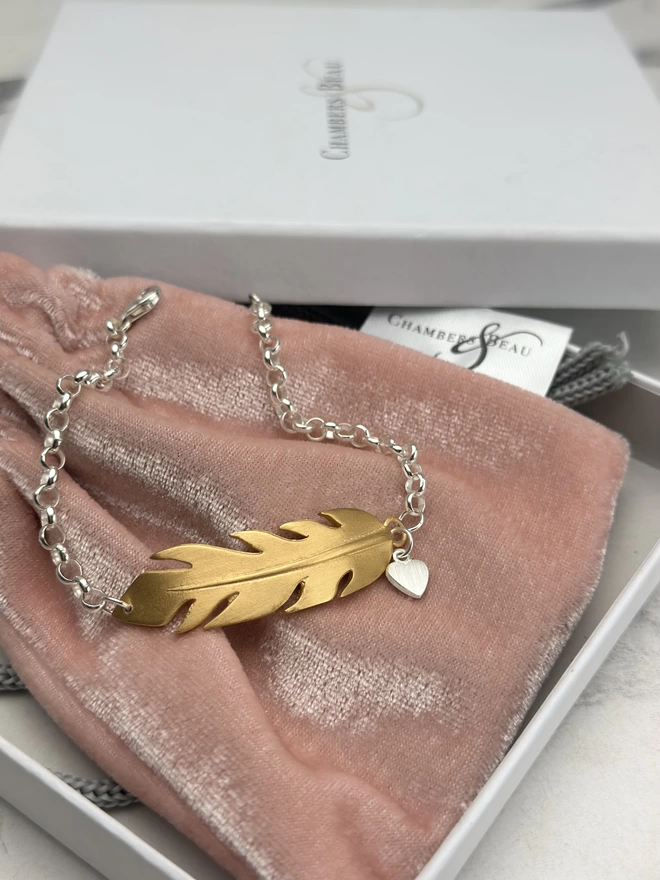 large gold feather charm bracelet on sterling silver belcher chain with silver mini heart charm. gift box and pouch