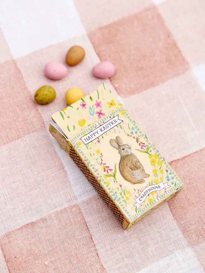 A Yellow box of Easter speckled eggs on a pink and white tablecloth