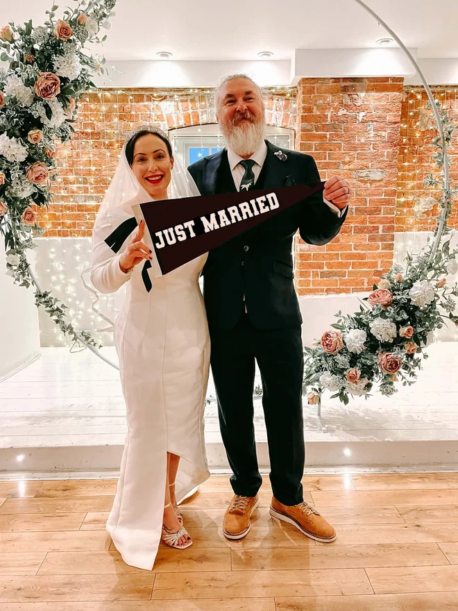 ' Just Married ' Wedding felt pennant flag in black and white held by a bride and groom in their wedding photo