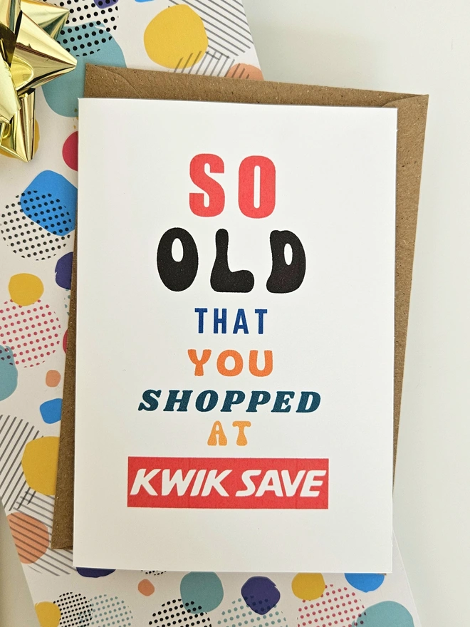 A photograph of the front of a humorous A6 greeting card illustrated using brightly coloured text and the retro shop logo. The text says so old you shopped at Kwik Save.