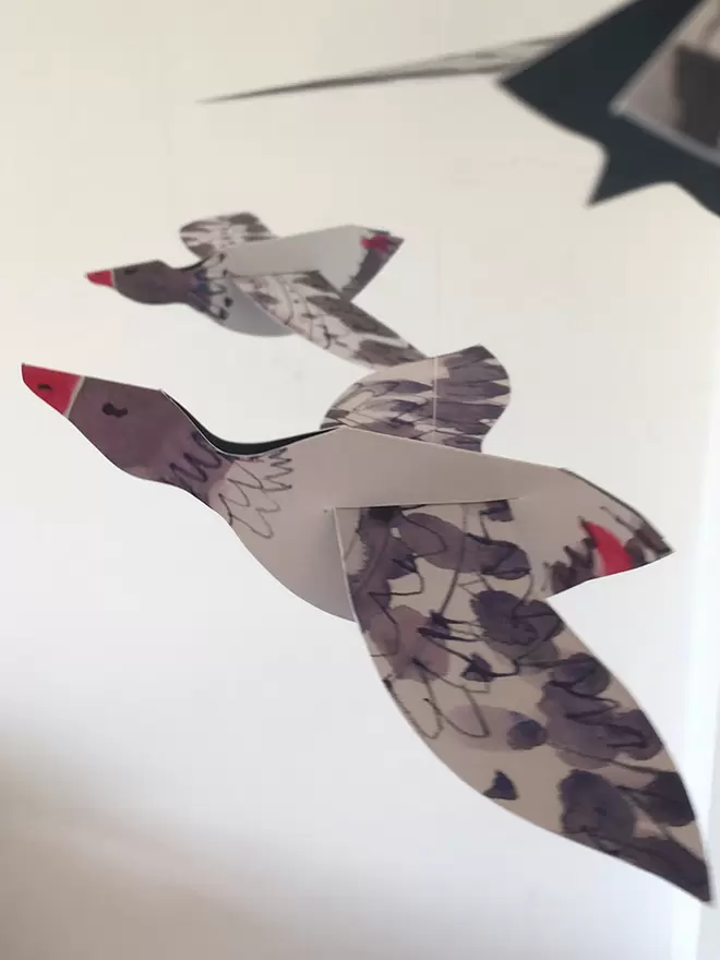 Esther Kent Three Geese illustrated paper mobile, hanging against a white wall.