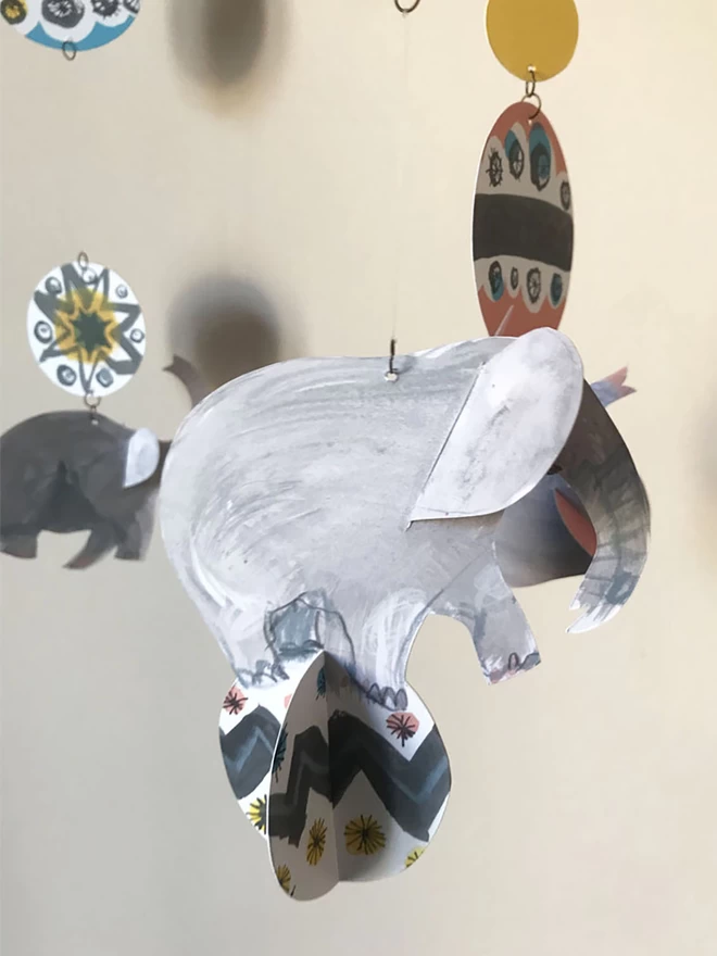 Esther Kent designed Circus Elephants mobile. Grey hand-drawn cut out elephants combined with mid-century circus patterns, casting shadows on a wall.