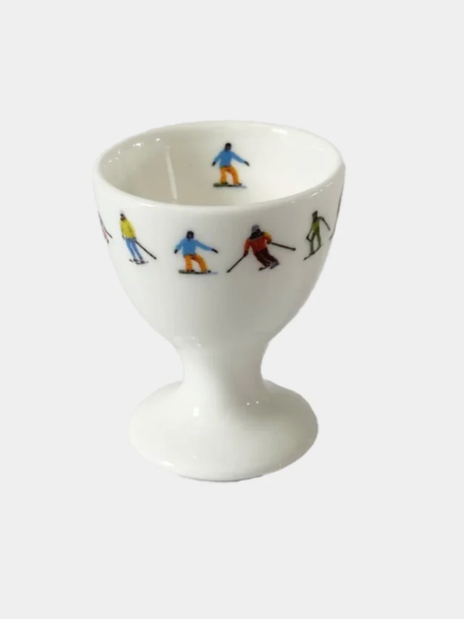Ski Chain Egg Cup. A white egg cup patterned with a chain of multicoloured skiers on its rim. It is set against a plain, white background.
