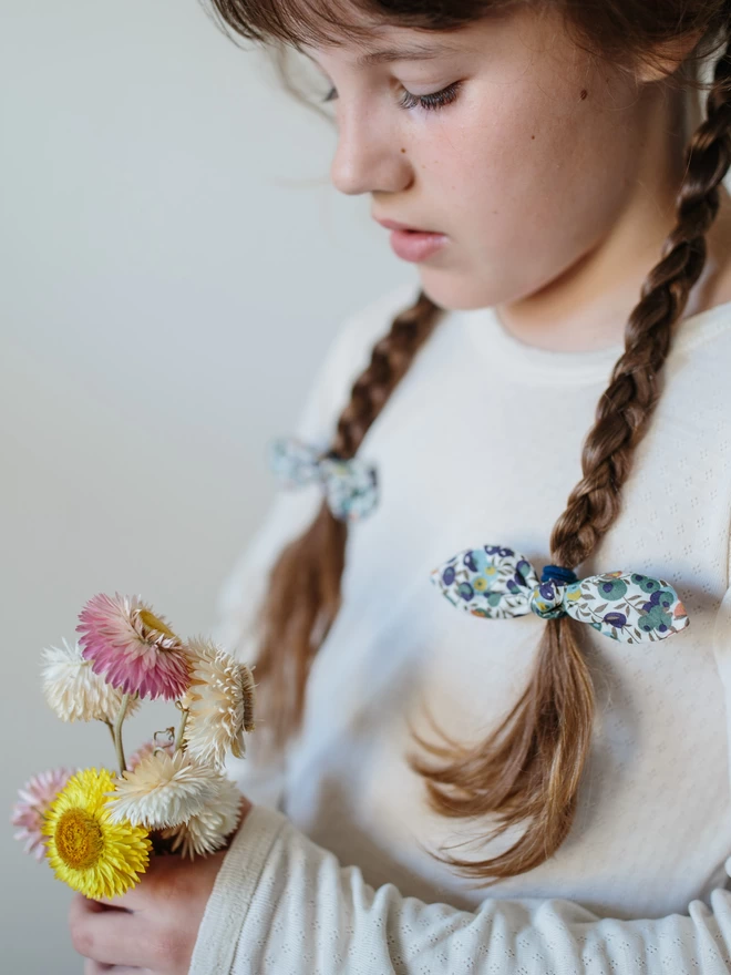 Little girl with long plaits and Liberty hair bobbles in them