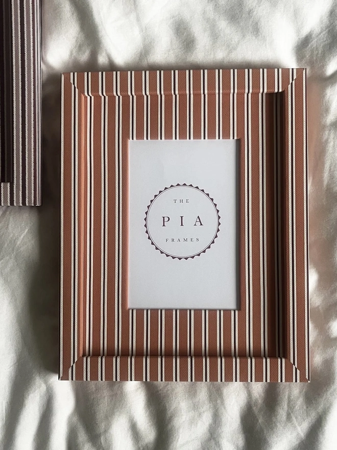 Tangerine & Burgundy Seaside Stripe Frame, a colourful striped frame sitting on a plain white surface. It is joined by another frame. 