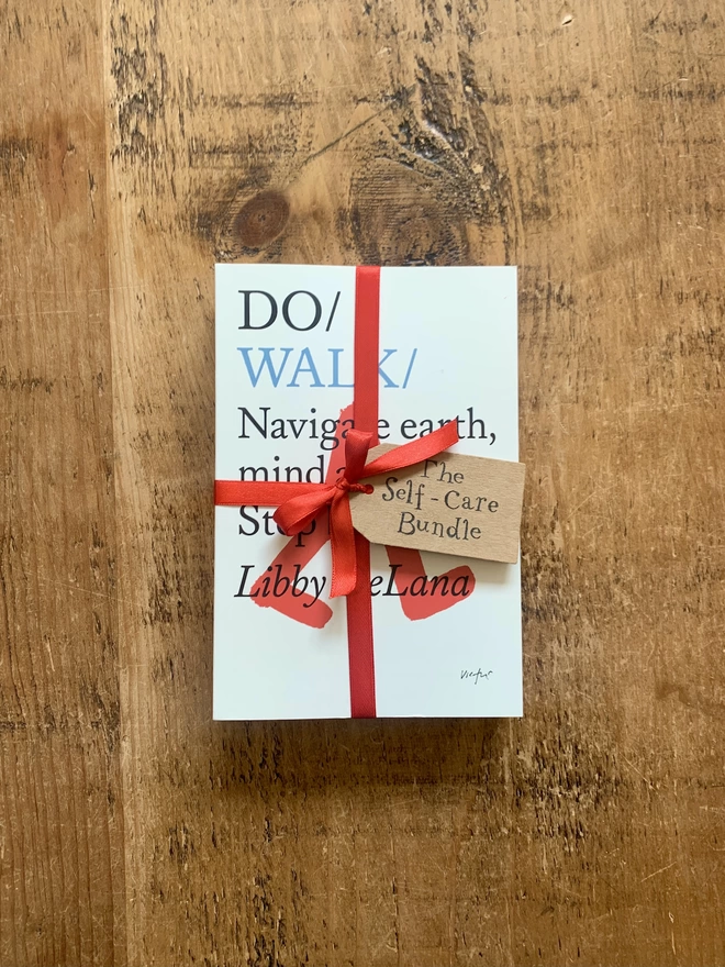 Book tied with a red ribbon and brown tag that reads 'The Self-Care Bundle'