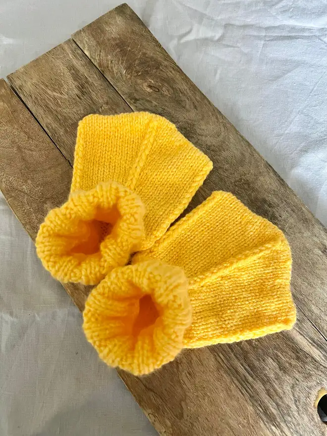 Duck Feet Socks, a pair of yellow duck feet socks sitting on a wooden board. 