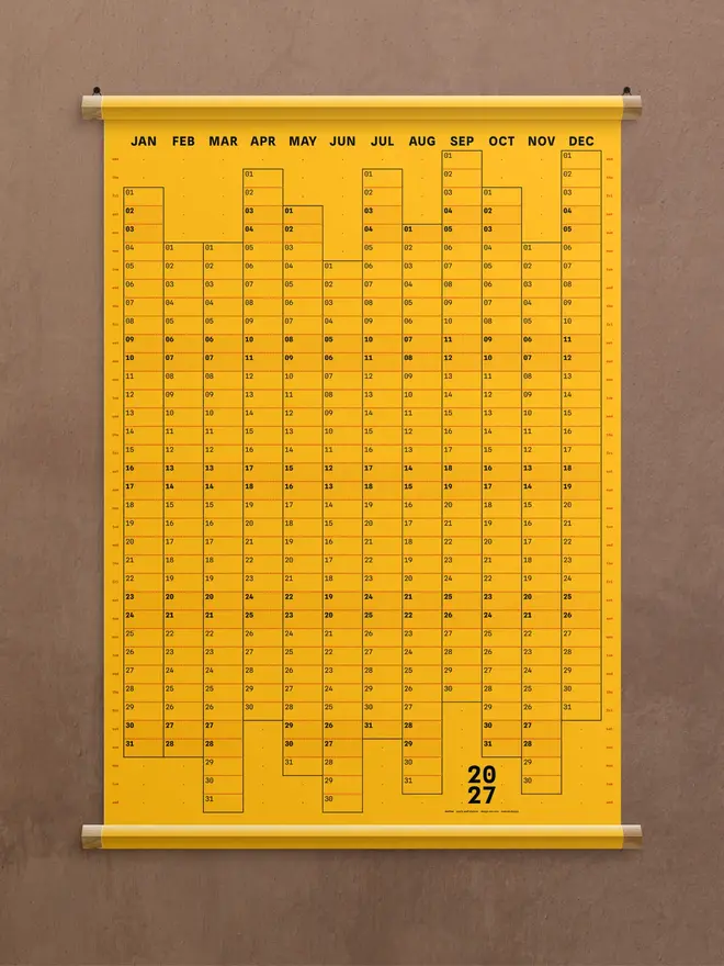 A golden yellow 'gold' Dotline 2027 yearly wall planner on brown wall