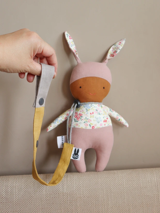 Handmade yellow linen toy strap with grey string and a toggle attached to a soft bunny doll.