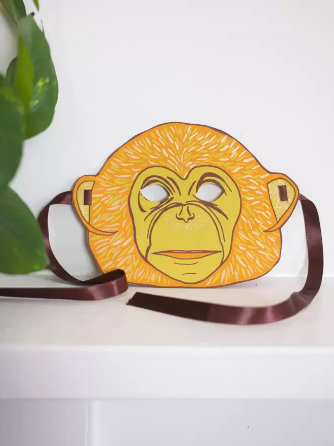 Full shot of image of orange monkey mask and brown ribbon