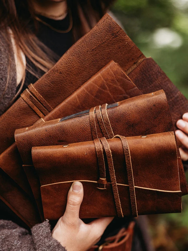 a6 leather pocket journal. a stack of light brown leather bound journals.