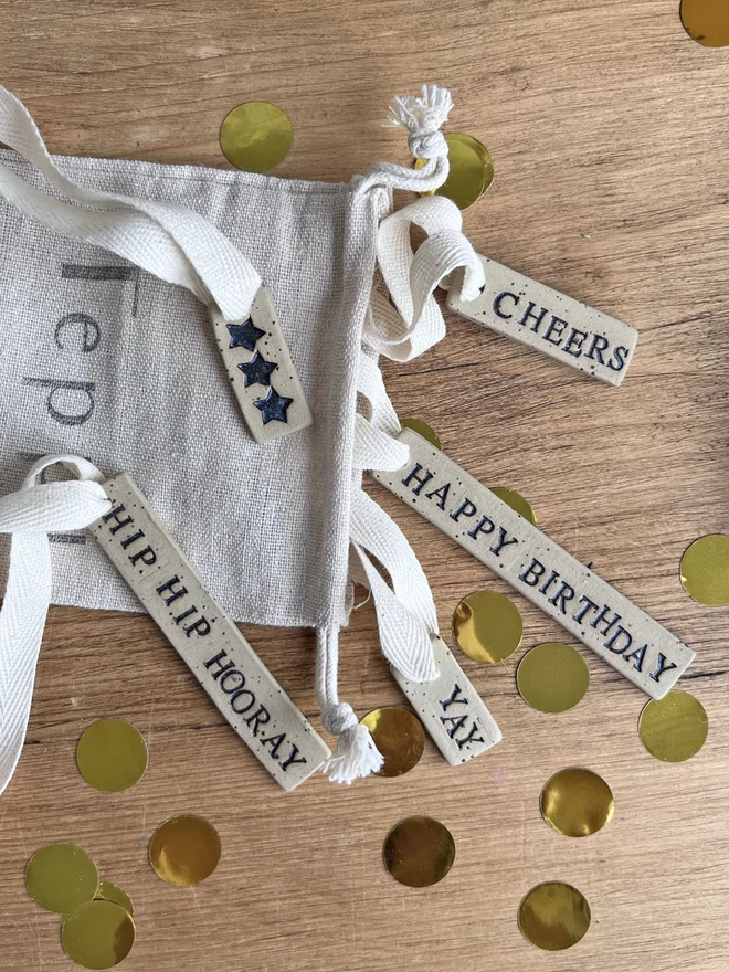 a selection of celebration themed ceramic tags poking out of a drawstring bag