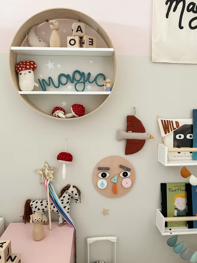 'magic' knitted wall hanging word sign for kids bedroom propped up on a shelf. 