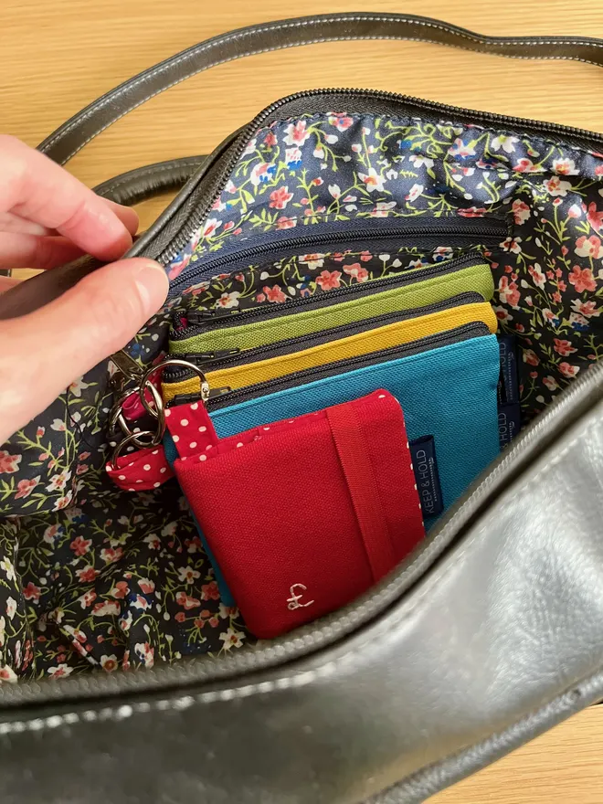 Set of 3 colourful keyring coin purses and 1 card wallet inside a black handbag, attached to inside zip.