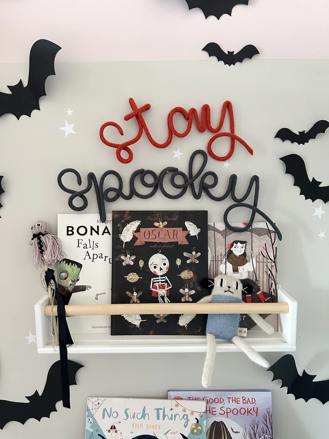 'Stay Spooky' hanging word decor above a shelf full of Hallow's Eve Books and Halloween decorations. 