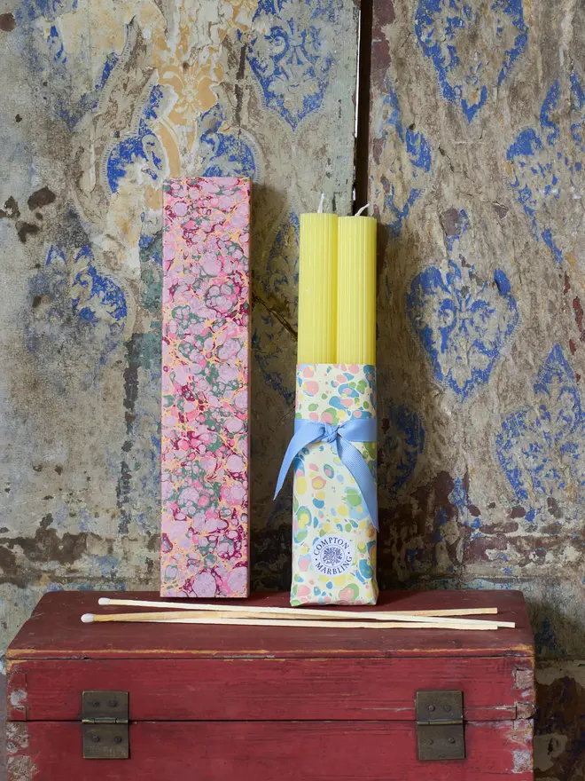 Scalloped yellow Candles with a box of long pink marbled matchbox