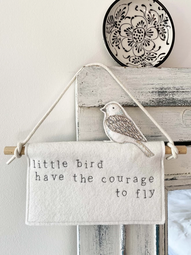 Little bird have the courage to fly felt banner hung on a door with plate