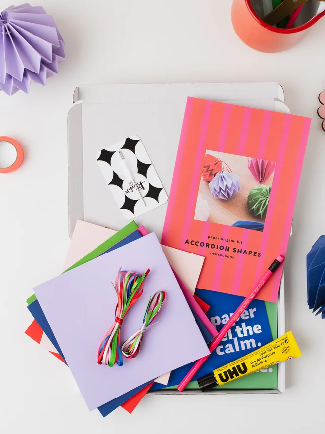 Open kit on a table surrounded by craft materials and paper ornaments.