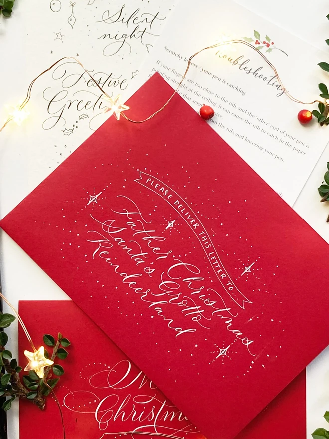 christmas modern calligraphy kit. red envelopes with white calligraphy written on the front.