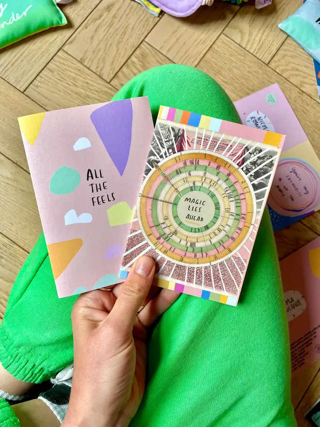 Nicola holds two of her popular cards against a pair of green trousers