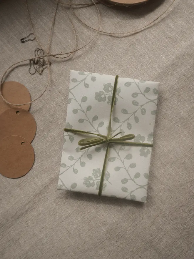 Gift wrapped parcel in botanical printed paper, finished with olive green velvet ribbon.