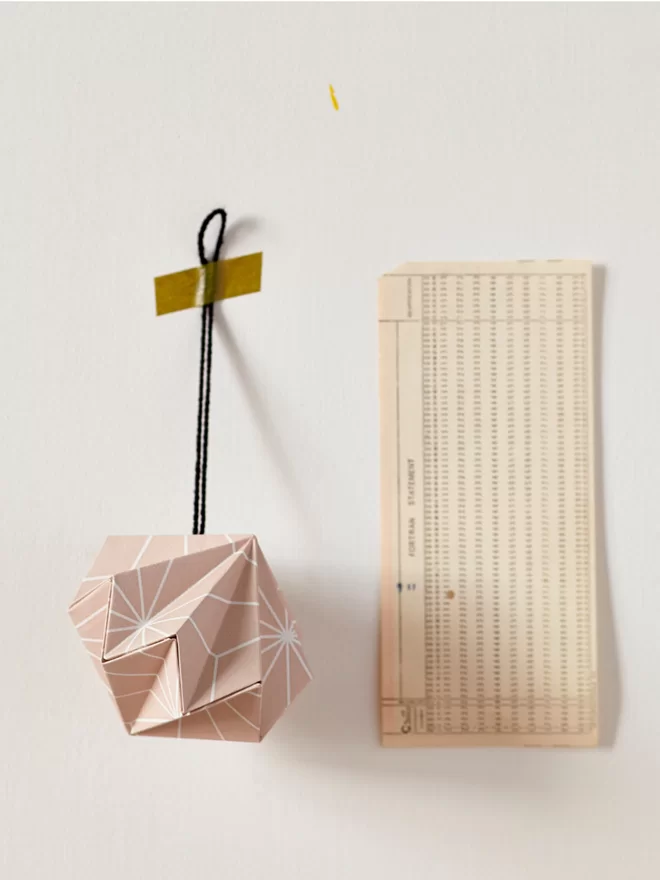 Paper diamond hung by washi tape, next to a scrap of vintage paper.