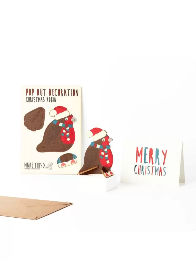 Robin Christmas decoration and Merry Christmas card and brown kraft envelope on a white background