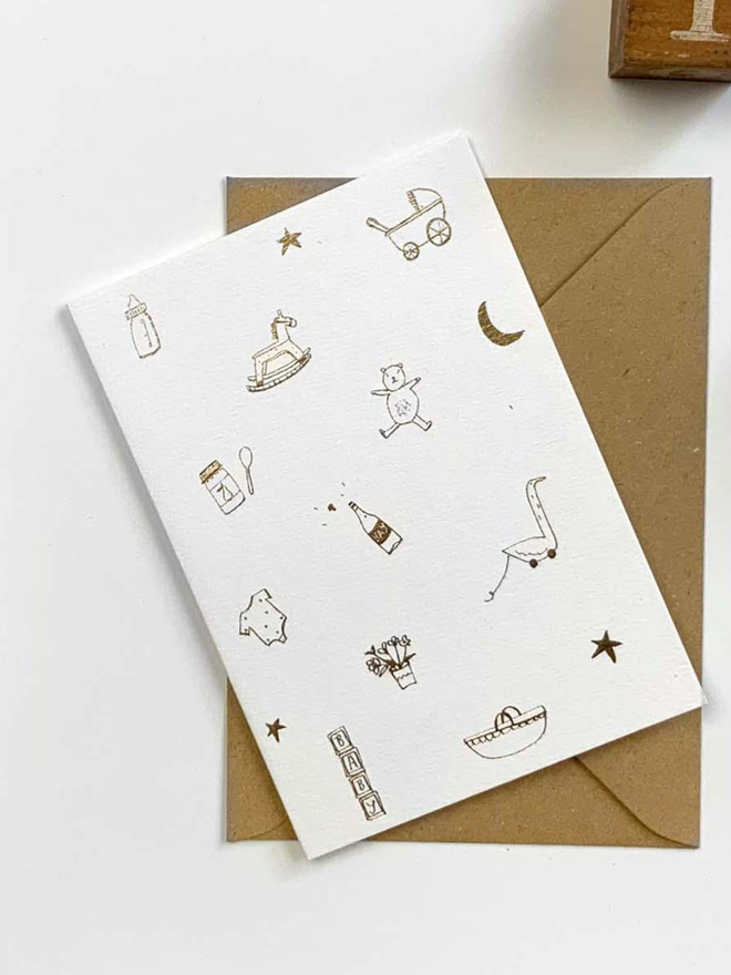 A6 Gold foil new baby card. Linear doodle of baby associated icons