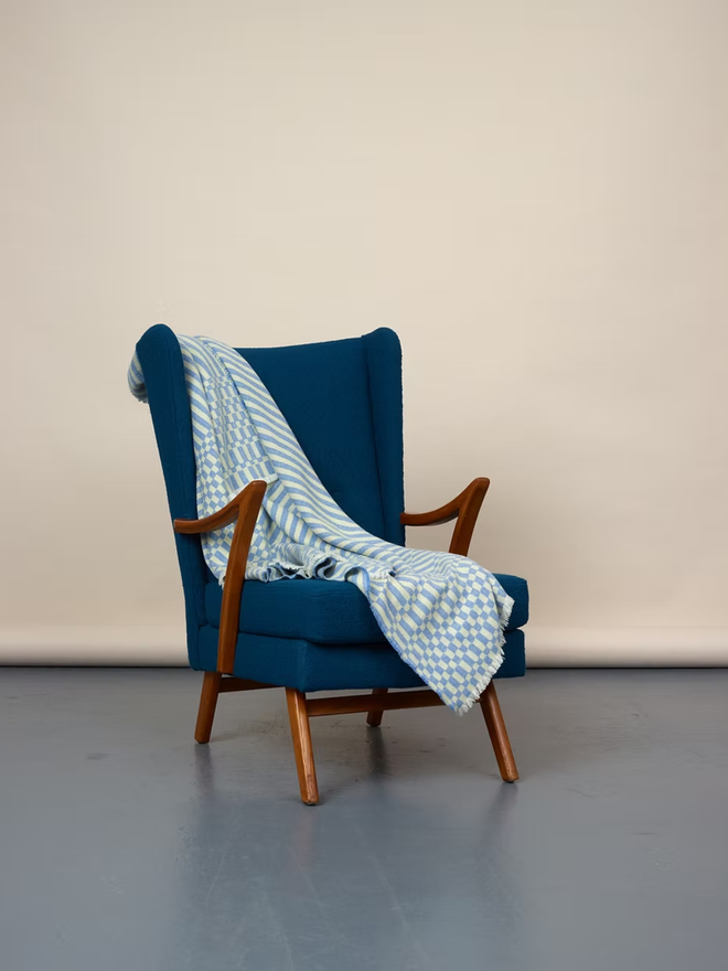 cham lambswool blanket. a blue and yellow striped blanket photographed thrown over a blue chair. 