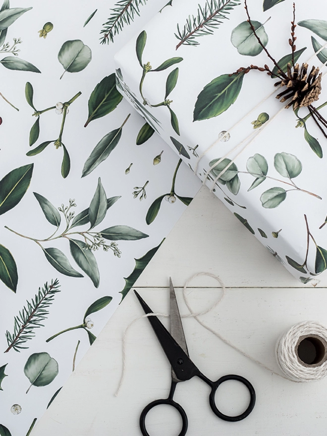 White base Christmas wrapping paper with a green foliage elements pattern