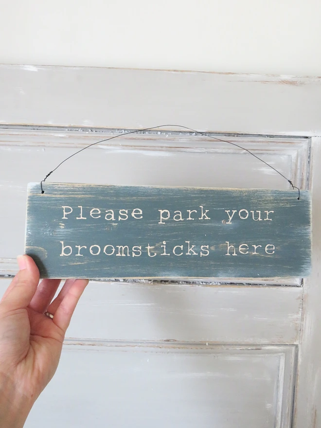 Distressed hand painted wooden sign decoration with broomstick parking message