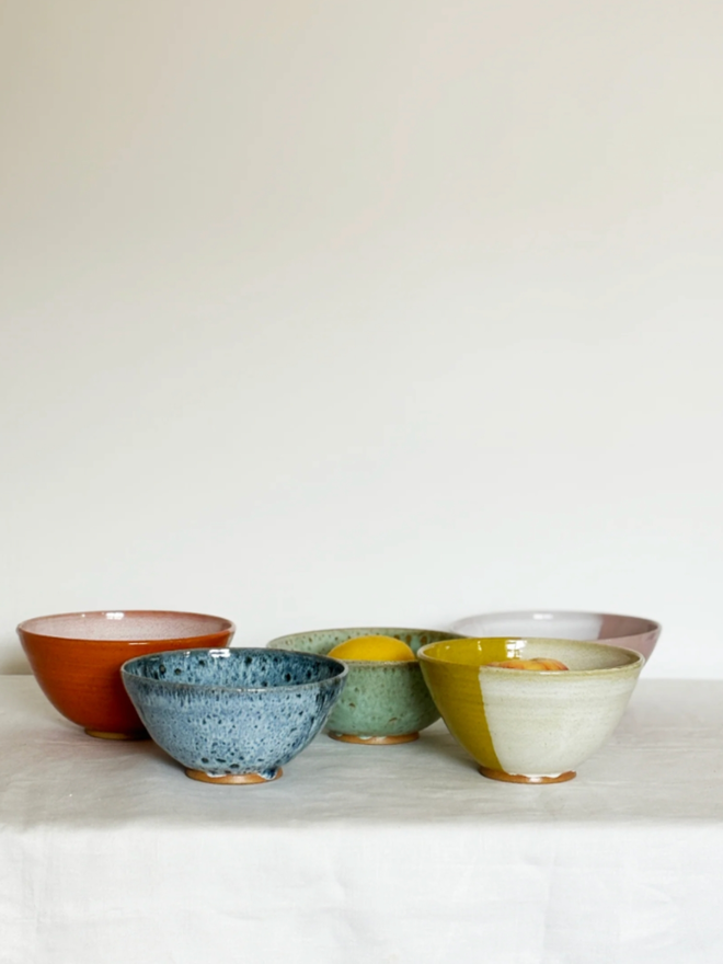 Cereal Bowl. A selection of cereal bowls in an array of colours. Left to right: Orange, Blue, Green, Pink, Yellow.