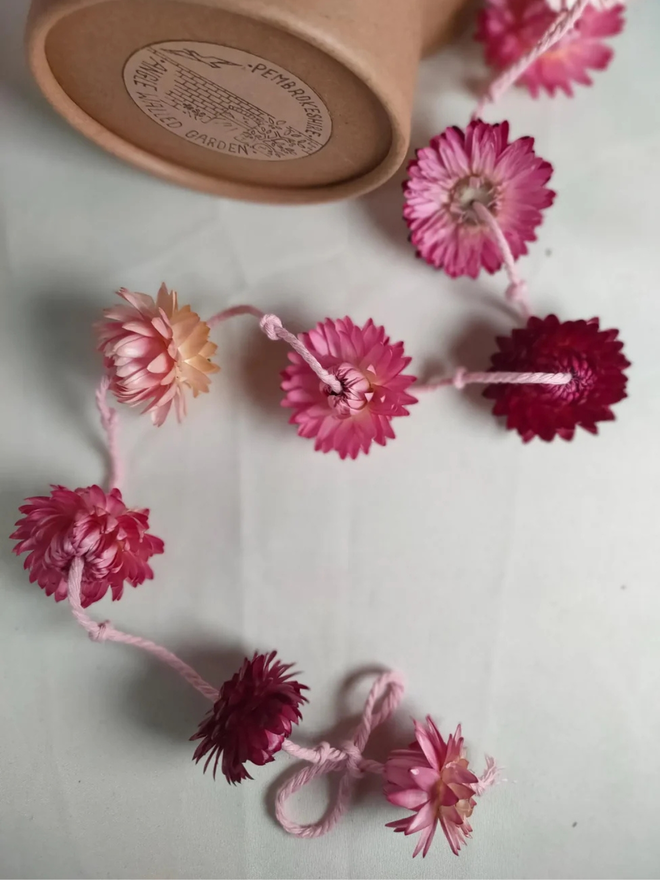 pretty pinks dried flower garland. pink dried flower garland laid out on white surface.