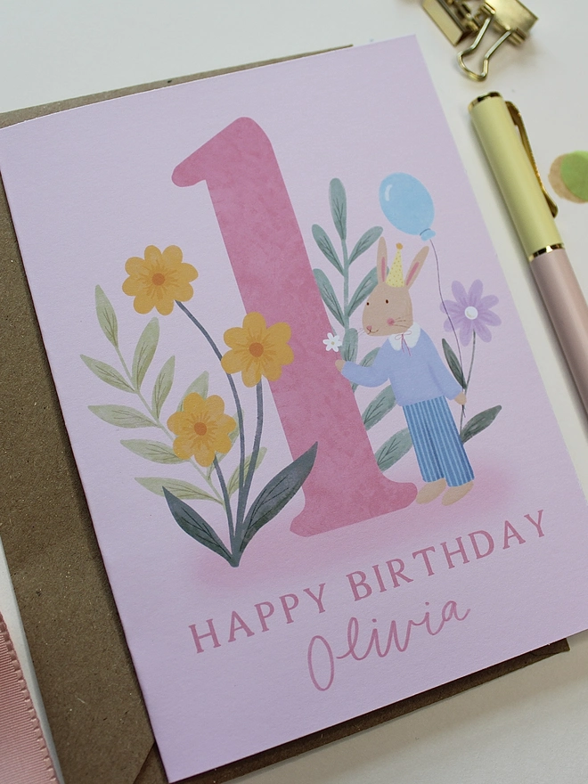 personalised floral 1st birthday card. pink 1st birthday card with illustrated rabbit and flowers.