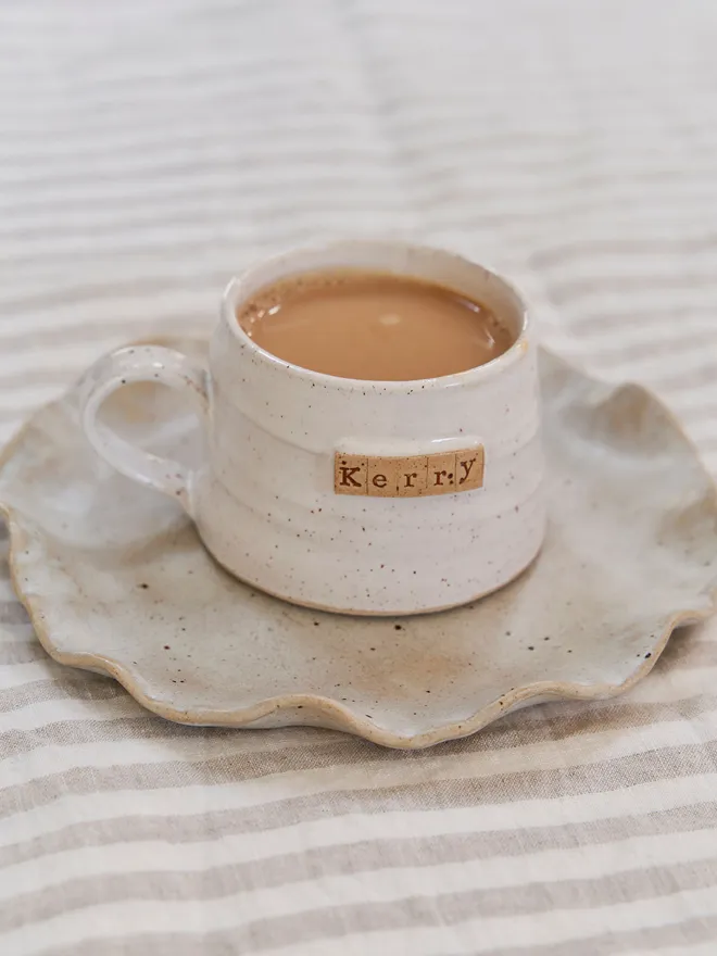 Personalised mug- 'Kerry' placed on a speckled plate on a stripped tablecloth 