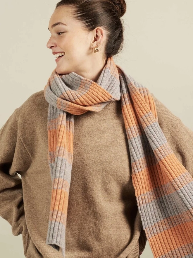 Lambswool Striped Scarf, a woman wearing a colourful striped scarf indoors. 