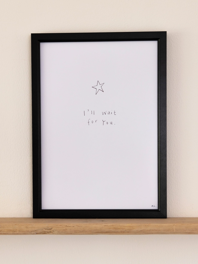 A simple line drawing star print in a black frame on a shelf.