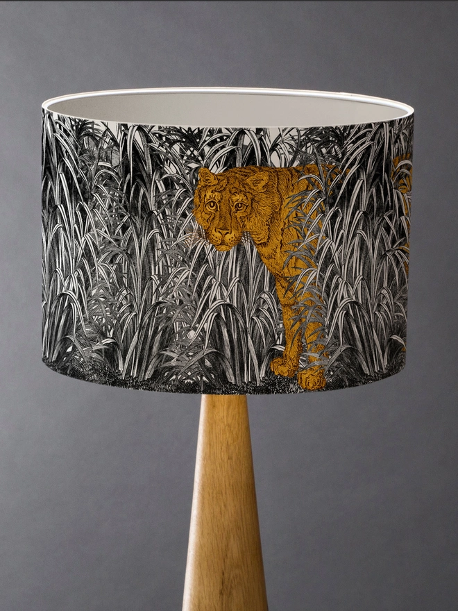 A decorative lampshade featuring an elegant tiger moving through tall tropical grasses, inspired by Henri Rousseau’s jungle paintings, with a rich botanical design.