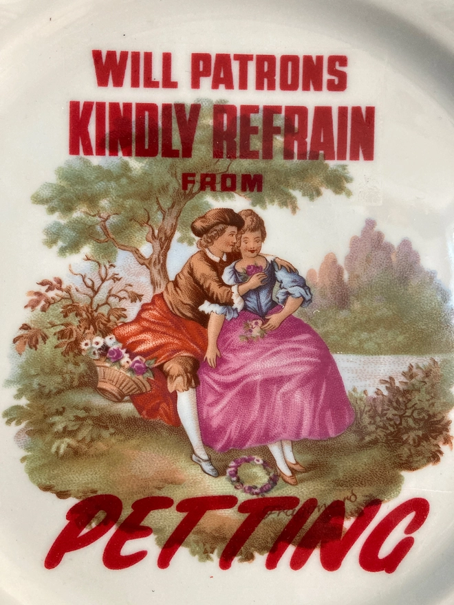 Decorative vintage plate featuring a young 'courting' couple with the slogan 'Will patrons kindly refrain from petting' across the plate.