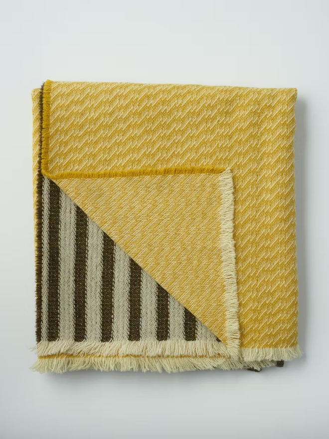 hiolair lambswool blanket. a yellow and brown striped blanket photographed folded against a white background.