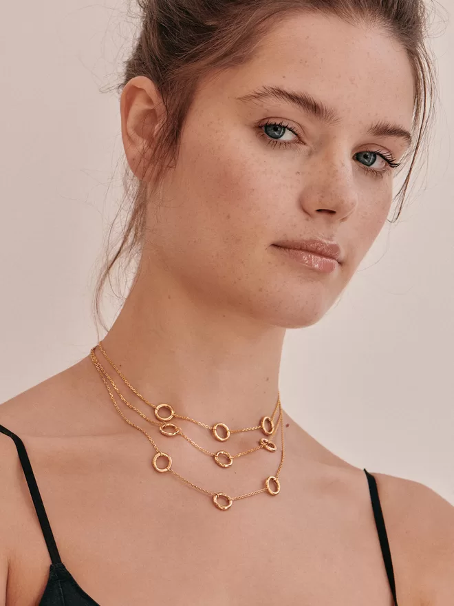 woman wearing three gold necklaces