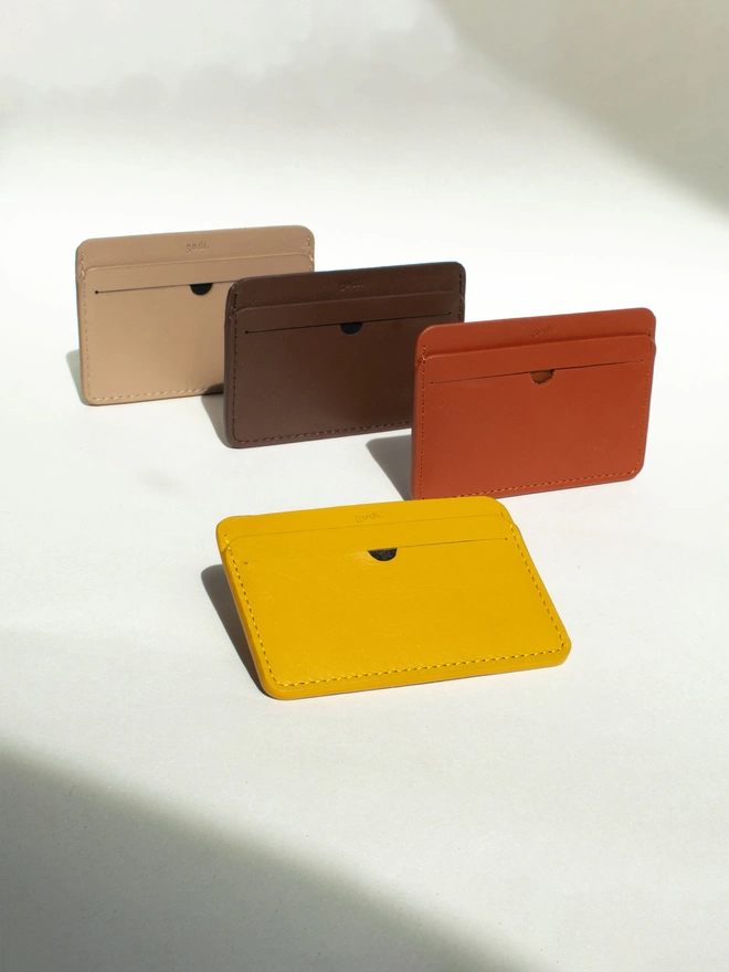 Cardholders laid out at an angle with a shadow formation. Colours include amber yellow, rust brown, coffee brown and sand in that order